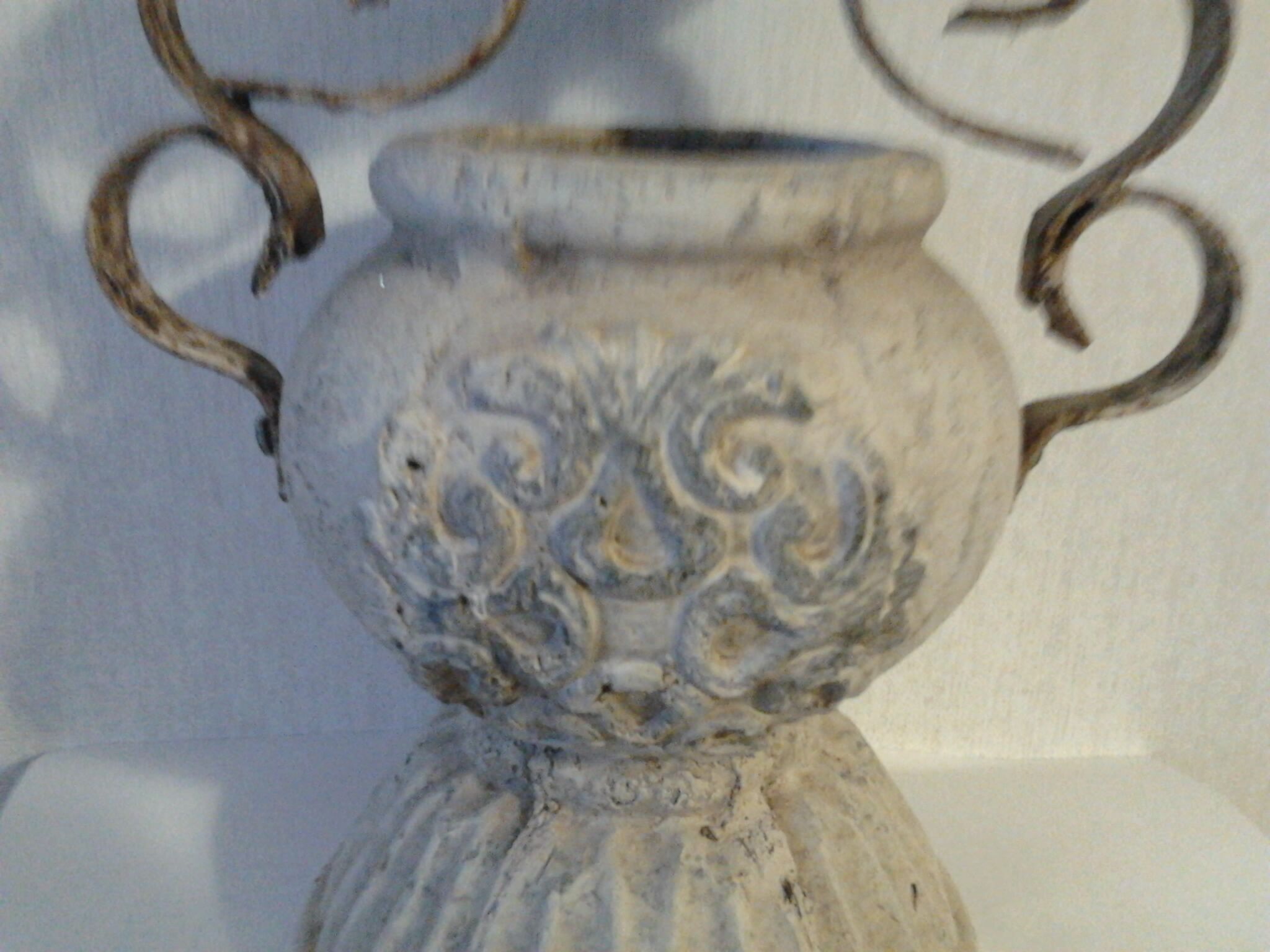 Ancient earthenware pot with sculptures on the sides and wrought iron cover