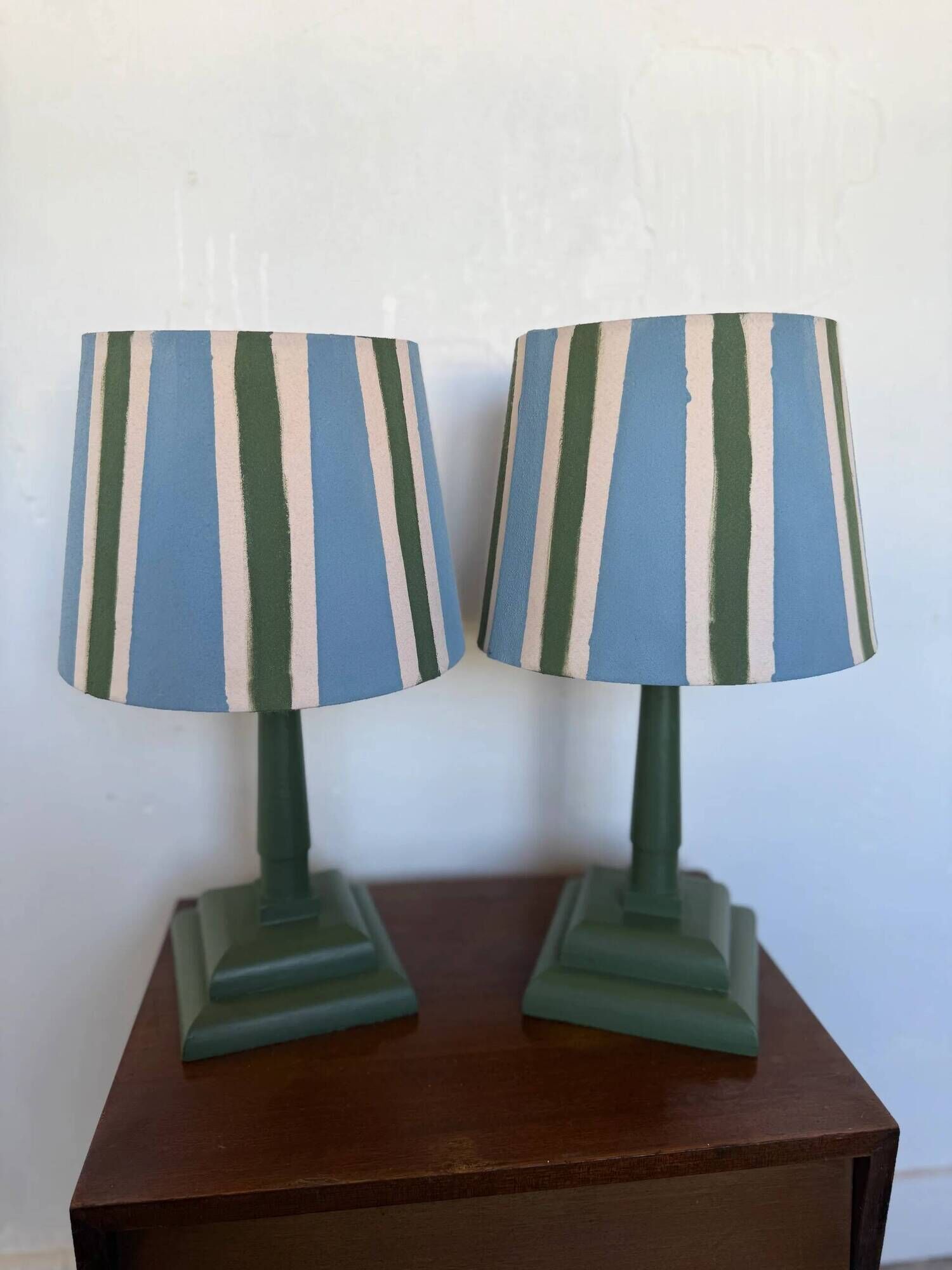 Pair of vintage wooden lamps with their striped beige, blue, and green shades.