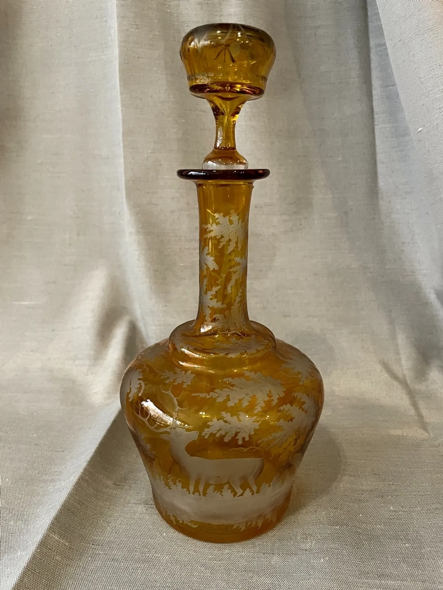 Amber bohemian glass liqueur carafe decorated with a stag in the forest.