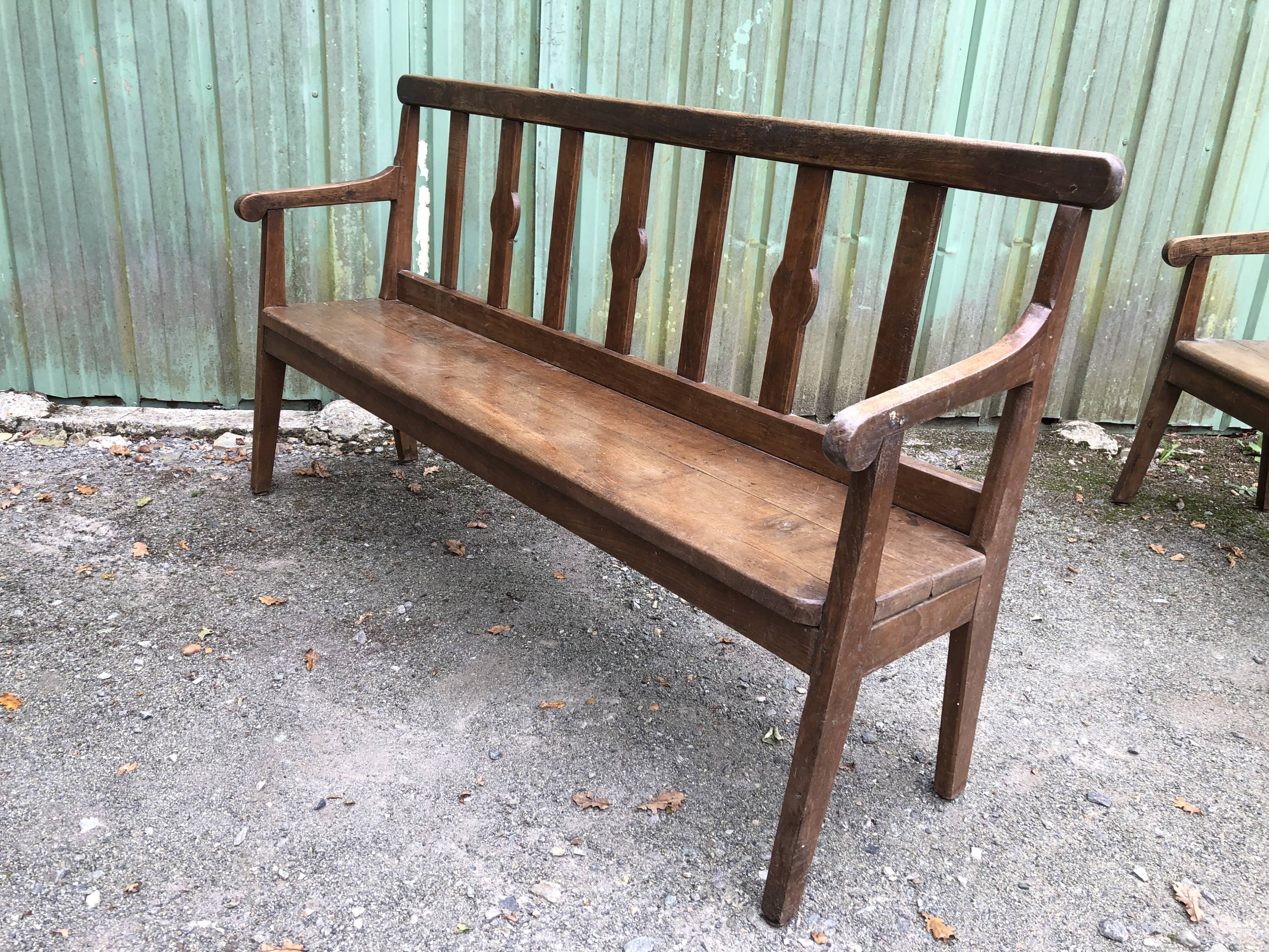 Duo of old solid oak benches with backs and armrests.