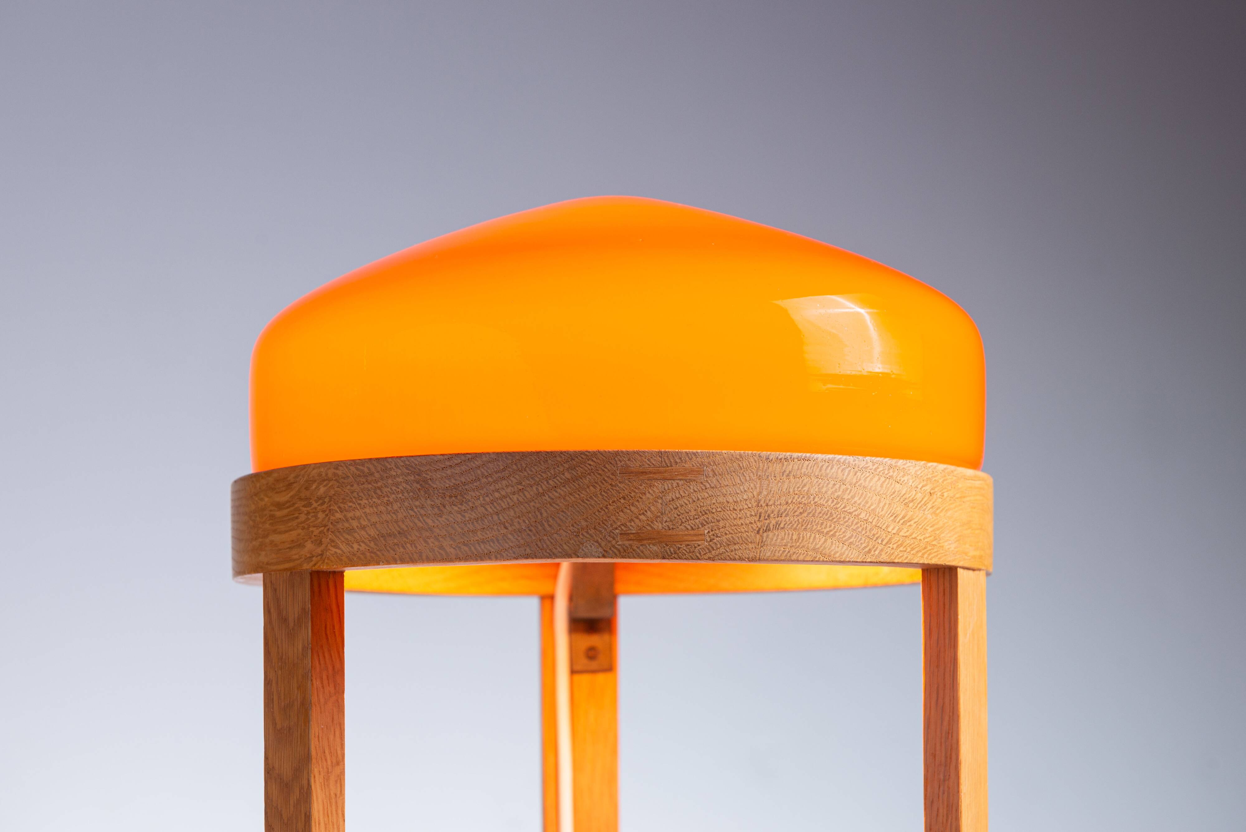 Bent oak wood table lamp with orange glass shade