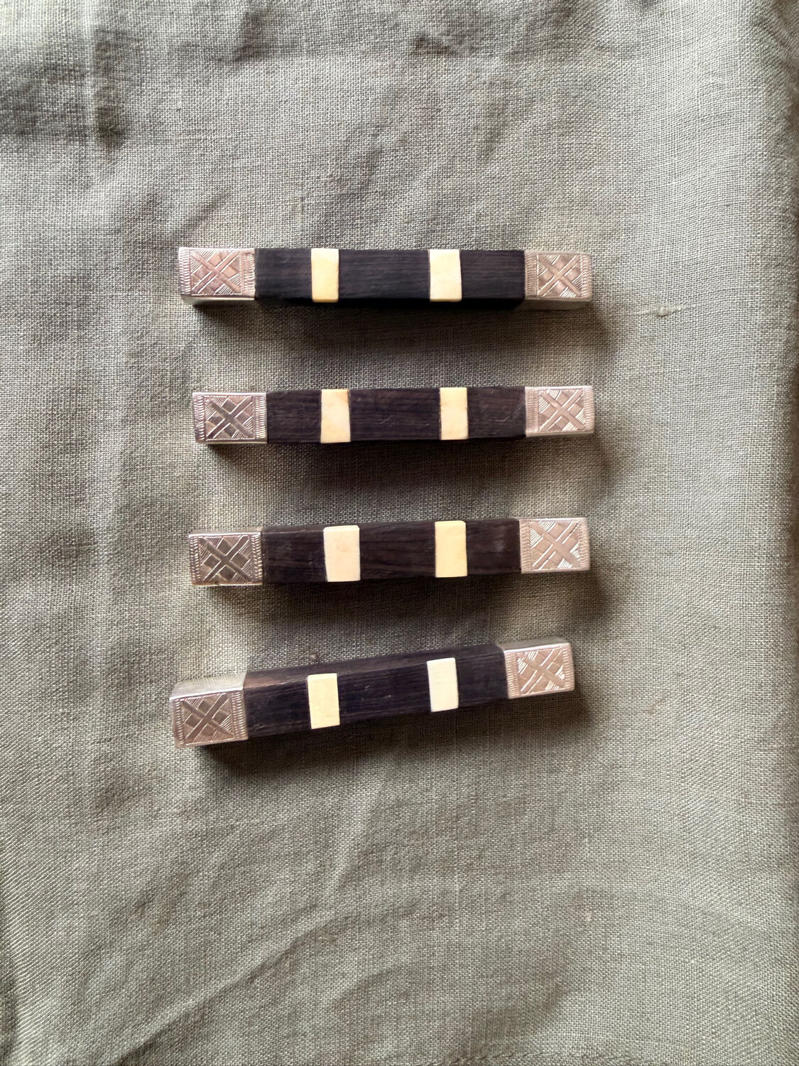 Lot 11 knife rests in ebony and silver-plated metal.