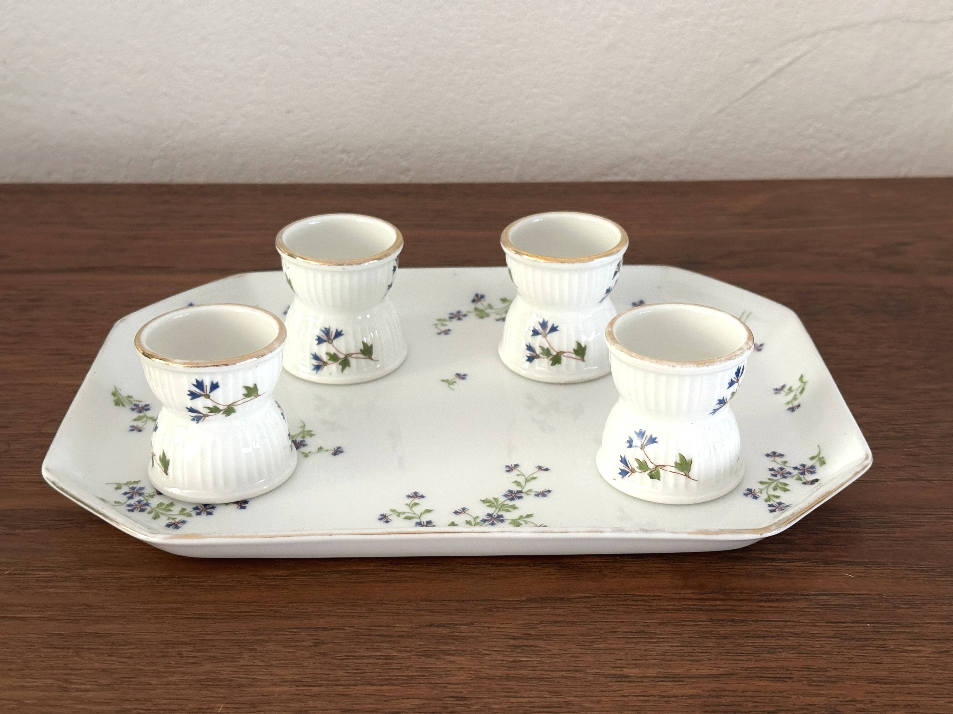 Egg cups on a Limoges porcelain tray by Bernardaud with a barbel decoration.