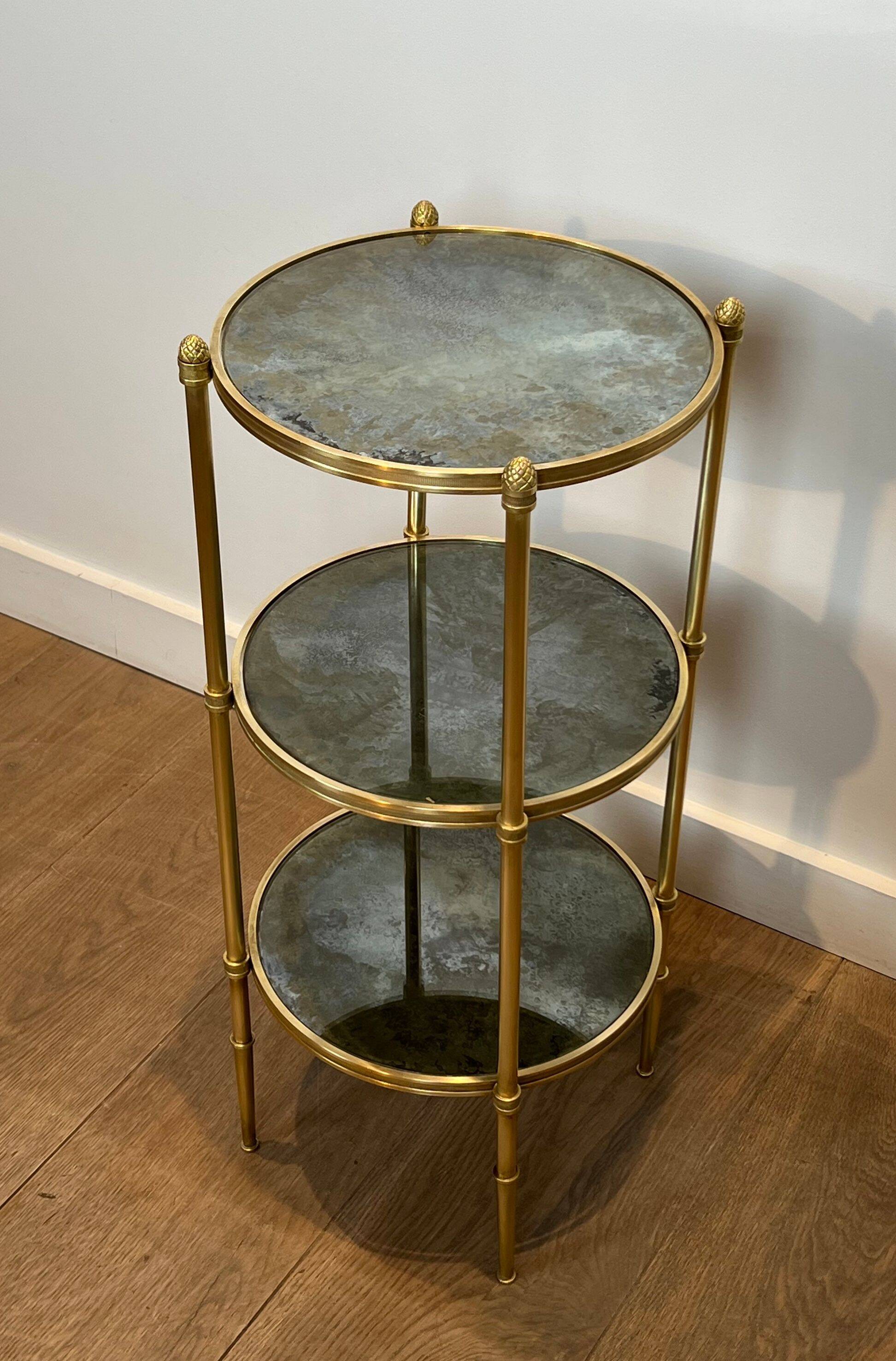 Round bronze side table with triple shelves of églomisé mirrors from Maison Baguès