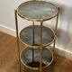 Round bronze side table with triple shelves of églomisé mirrors from Maison Baguès