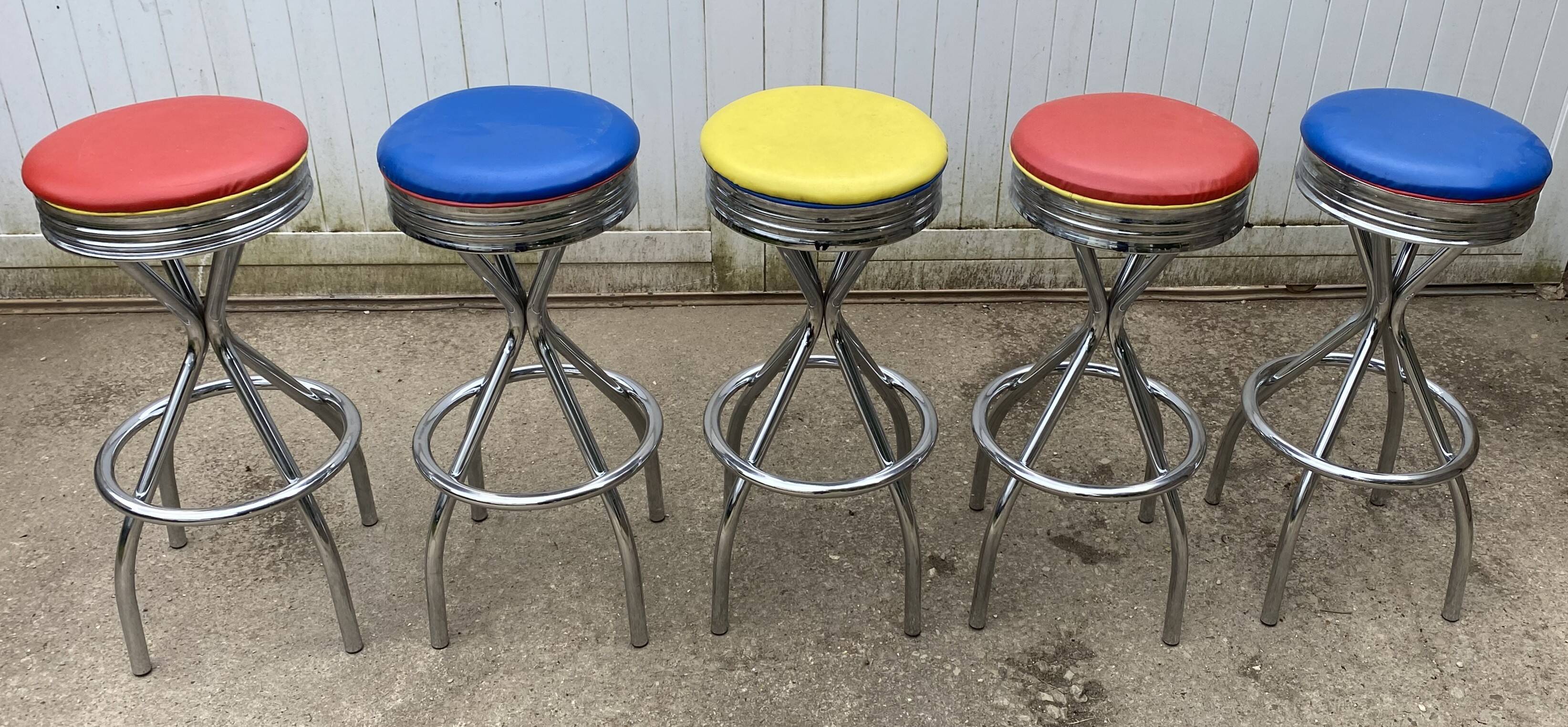 Set of 5 vintage swivel bar stools in blue, red, orange, and yellow.
