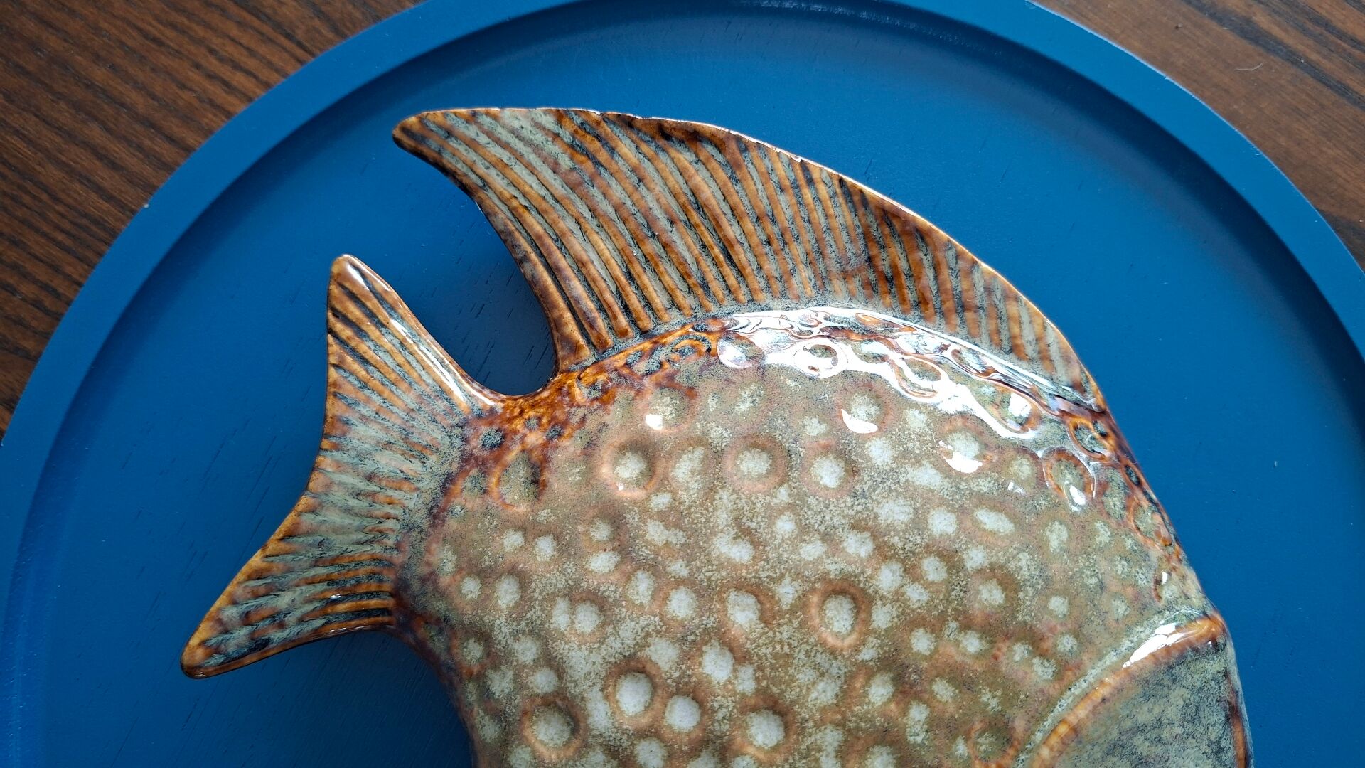 Vallauris ceramic wall sculpture of a relief fish on a blue plaque.