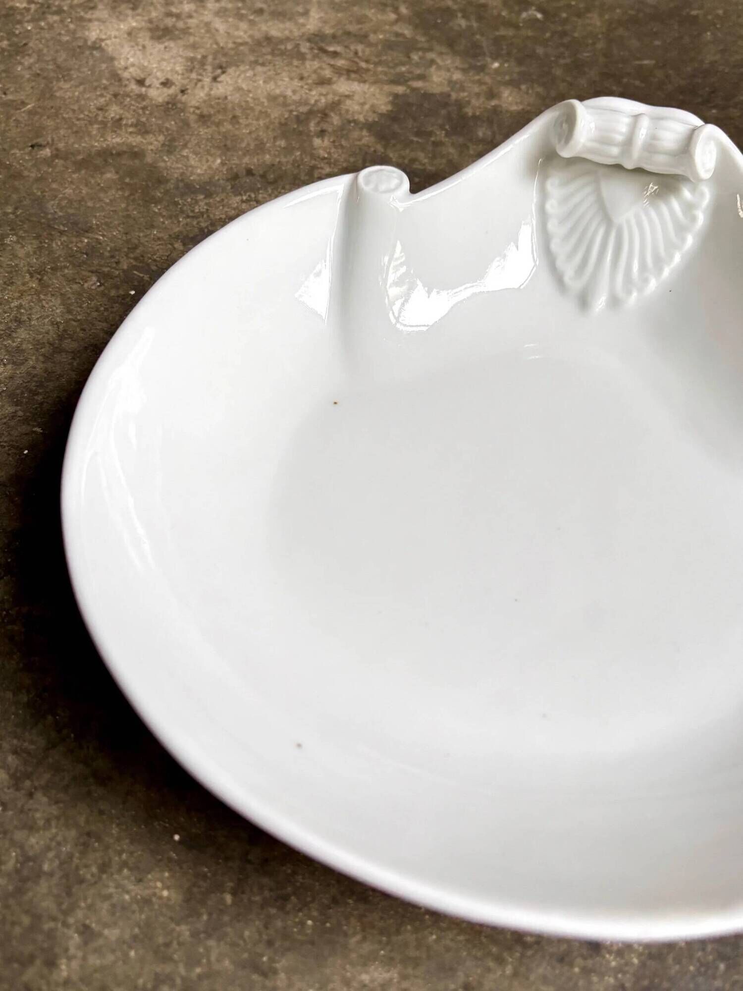 Small, shallow porcelain dish shaped like a seashell