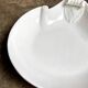 Small, shallow porcelain dish shaped like a seashell