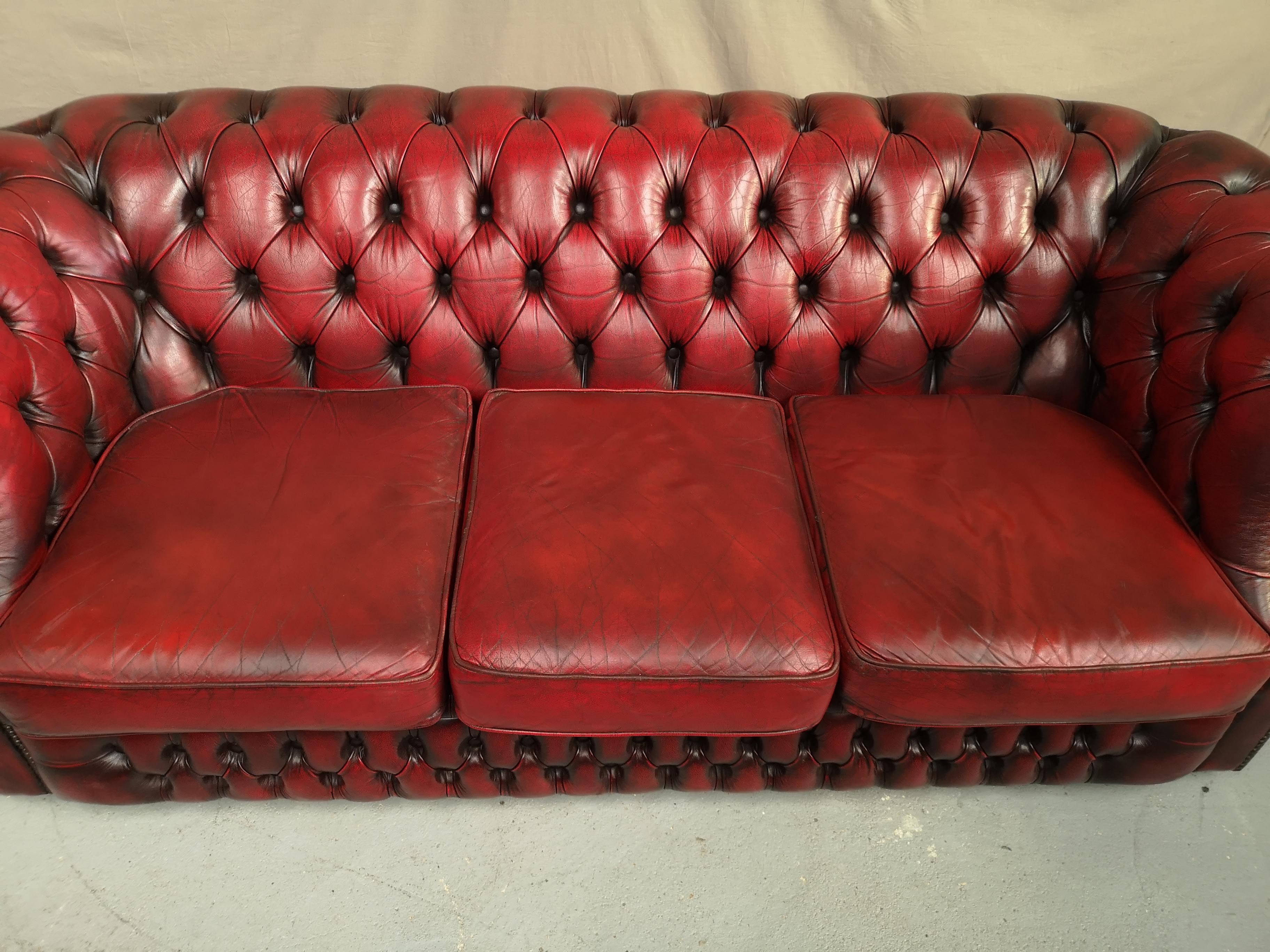 Three-seater curved red leather chesterfield sofa