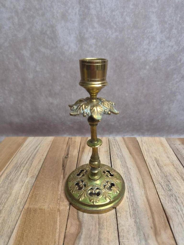 Antique brass candlestick with patina, openwork vintage foliage decoration.