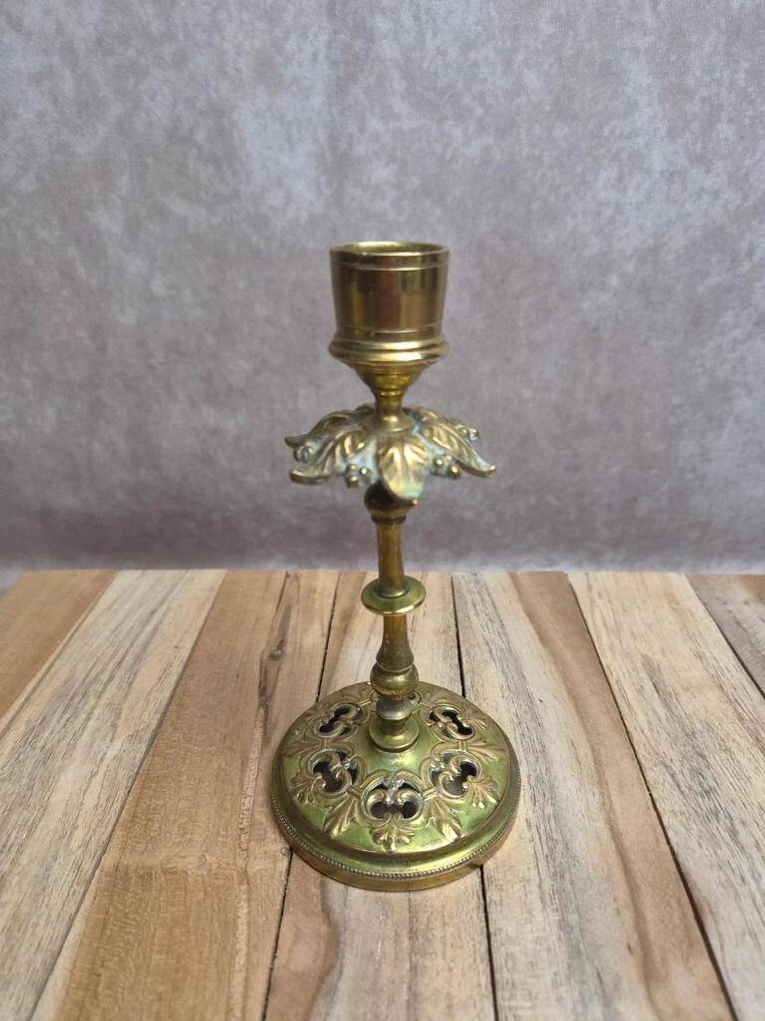 Antique brass candlestick with patina, openwork vintage foliage decoration.