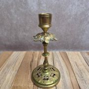 Antique brass candlestick with patina, openwork vintage foliage decoration.