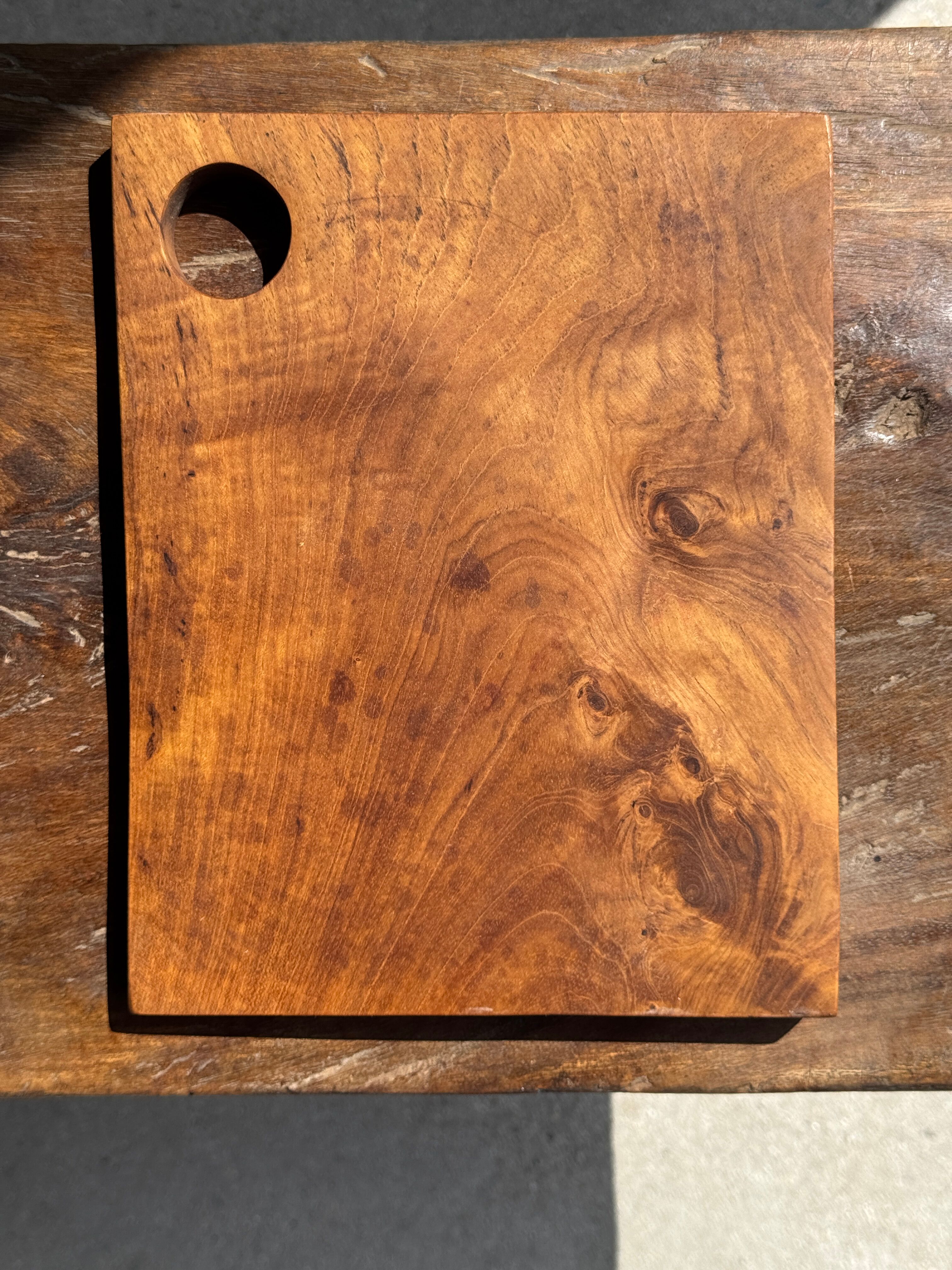 Small rectangular teak monoxyle cutting board with a circular handle.