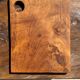 Small rectangular teak monoxyle cutting board with a circular handle.