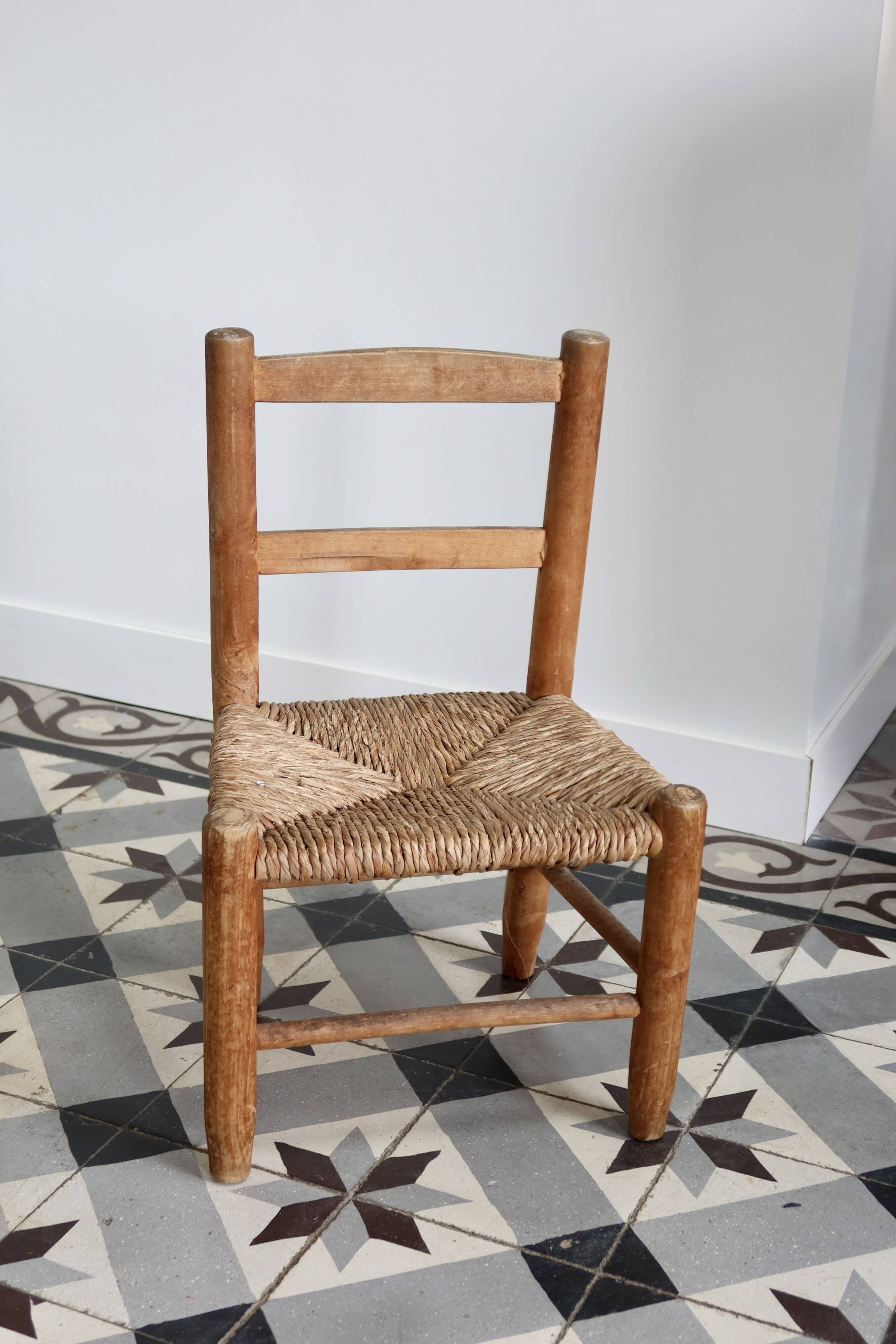 Antique wooden child's chair with a straw seat.