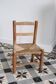 Antique wooden child's chair with a straw seat.