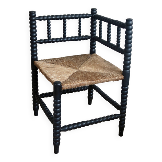 Antique black turned wood corner chair with a straw seat.