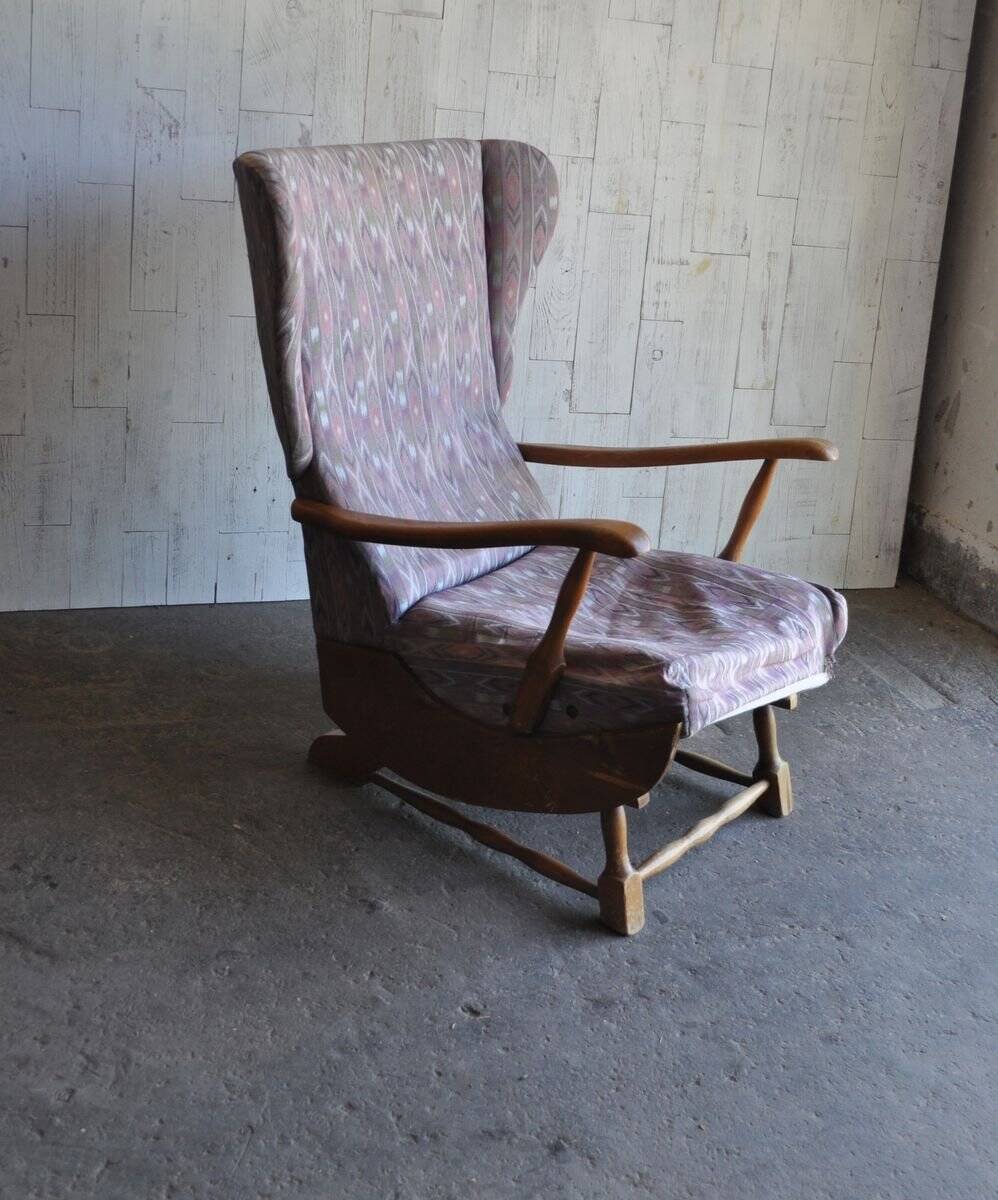 Vintage brown wooden rocking chair from the 1950s, wingback backrest and rocking base.
