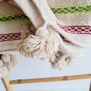 Moroccan plaid made of handwoven wool, decorated with stripes and pom-poms.