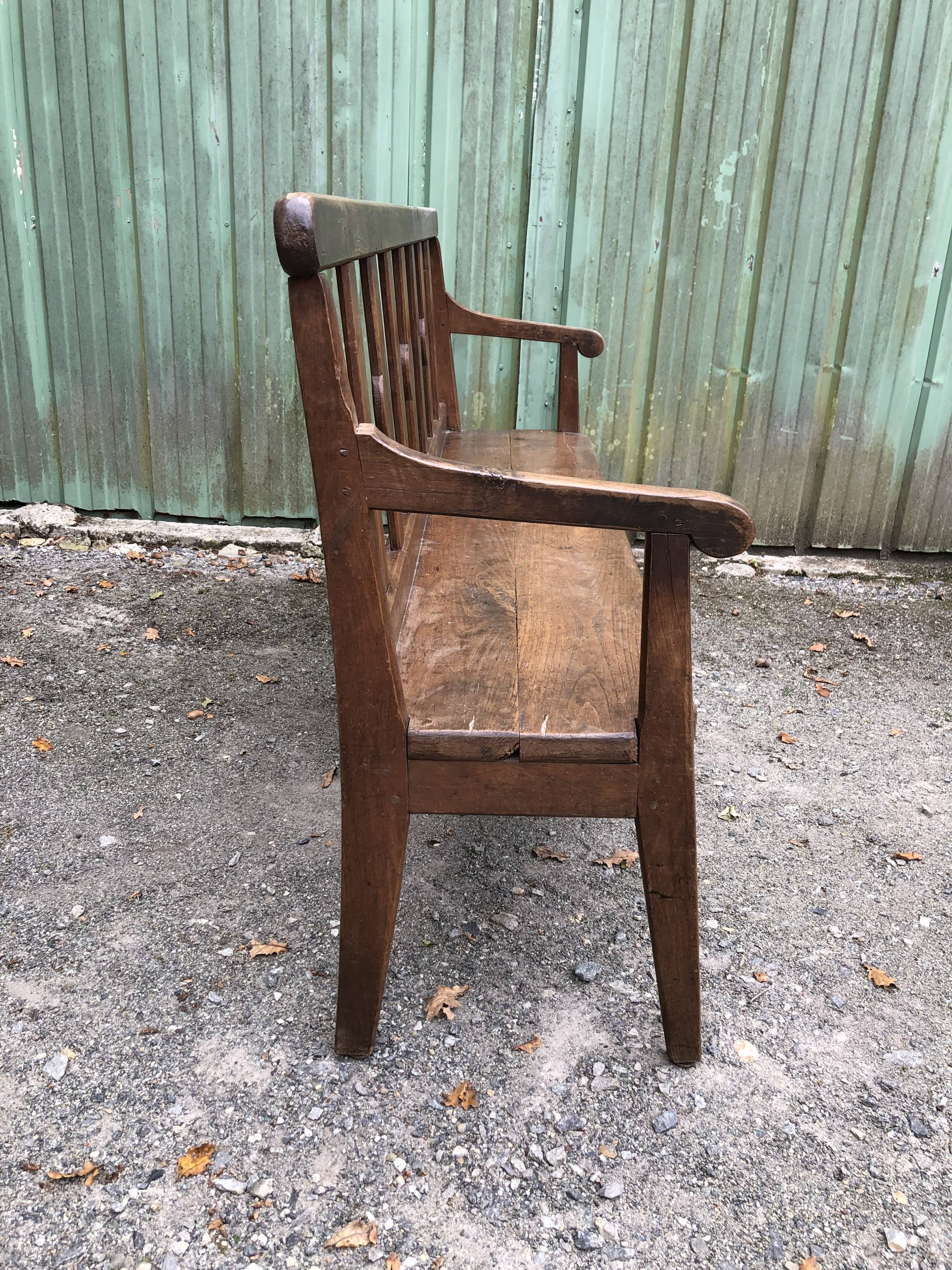 Duo of old solid oak benches with backs and armrests.