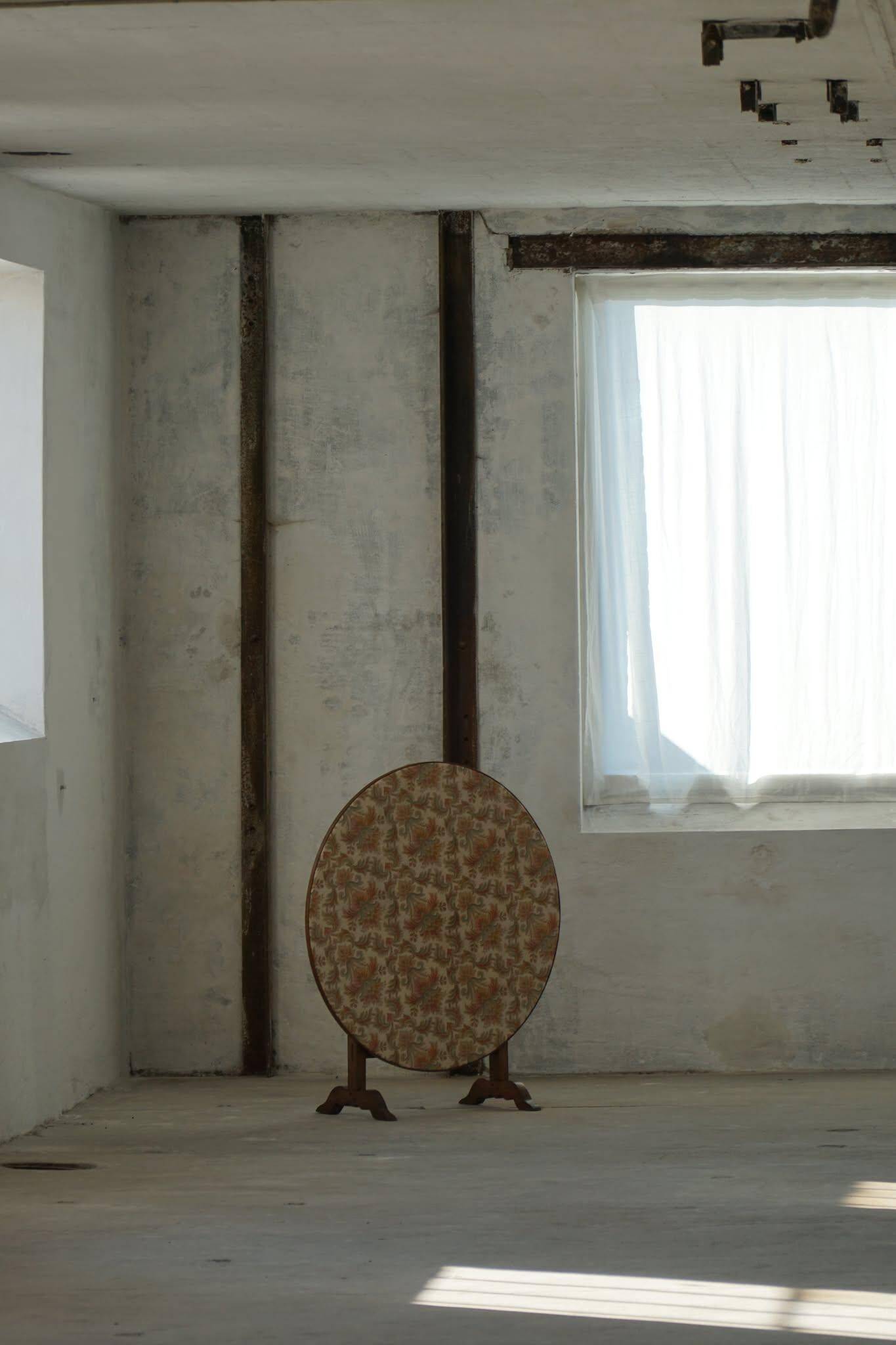 19th-century French round wine table with an adjustable top and floral textile surface.