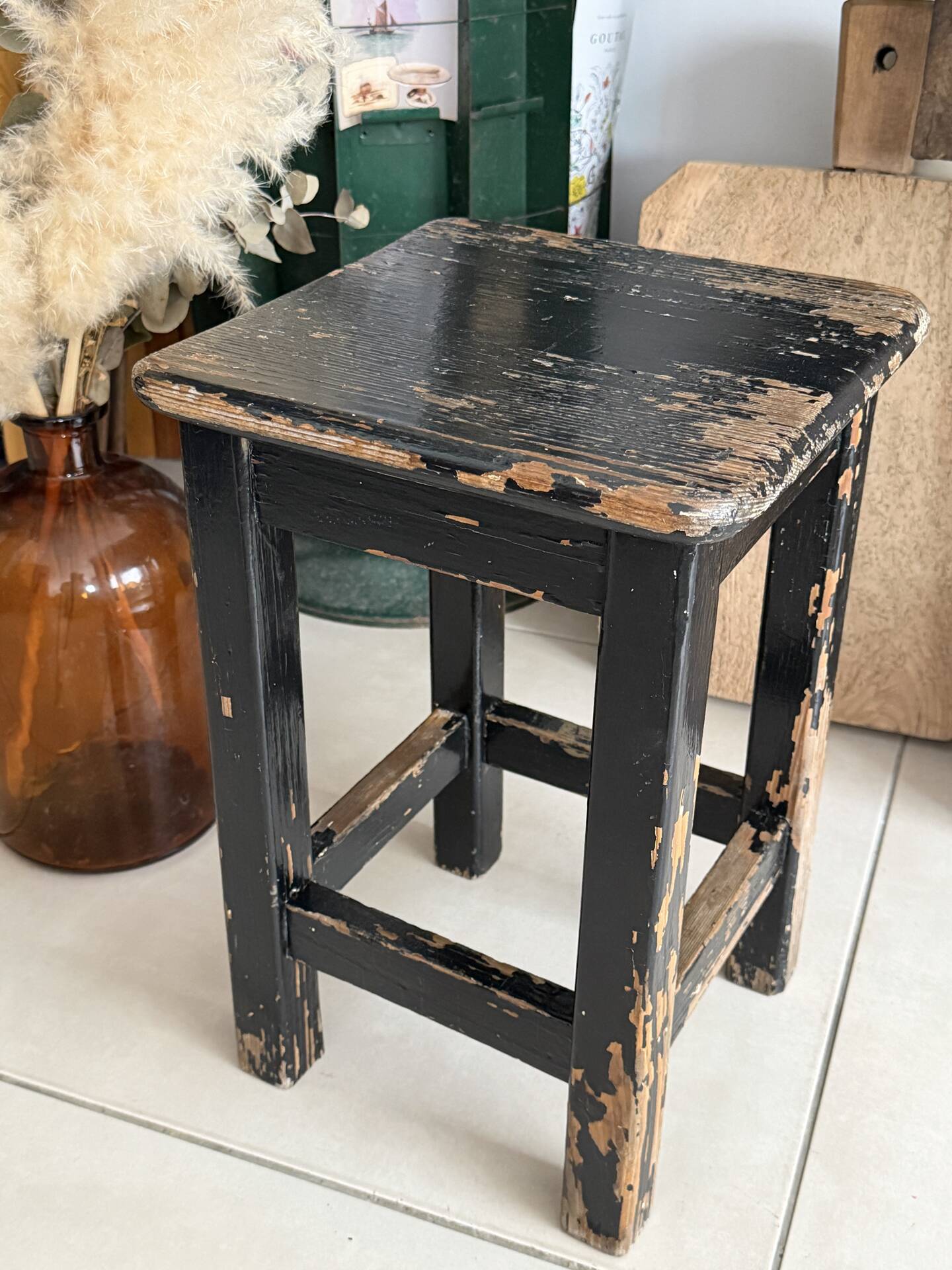 Solid wood stool with a worn black patina.