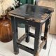 Solid wood stool with a worn black patina.