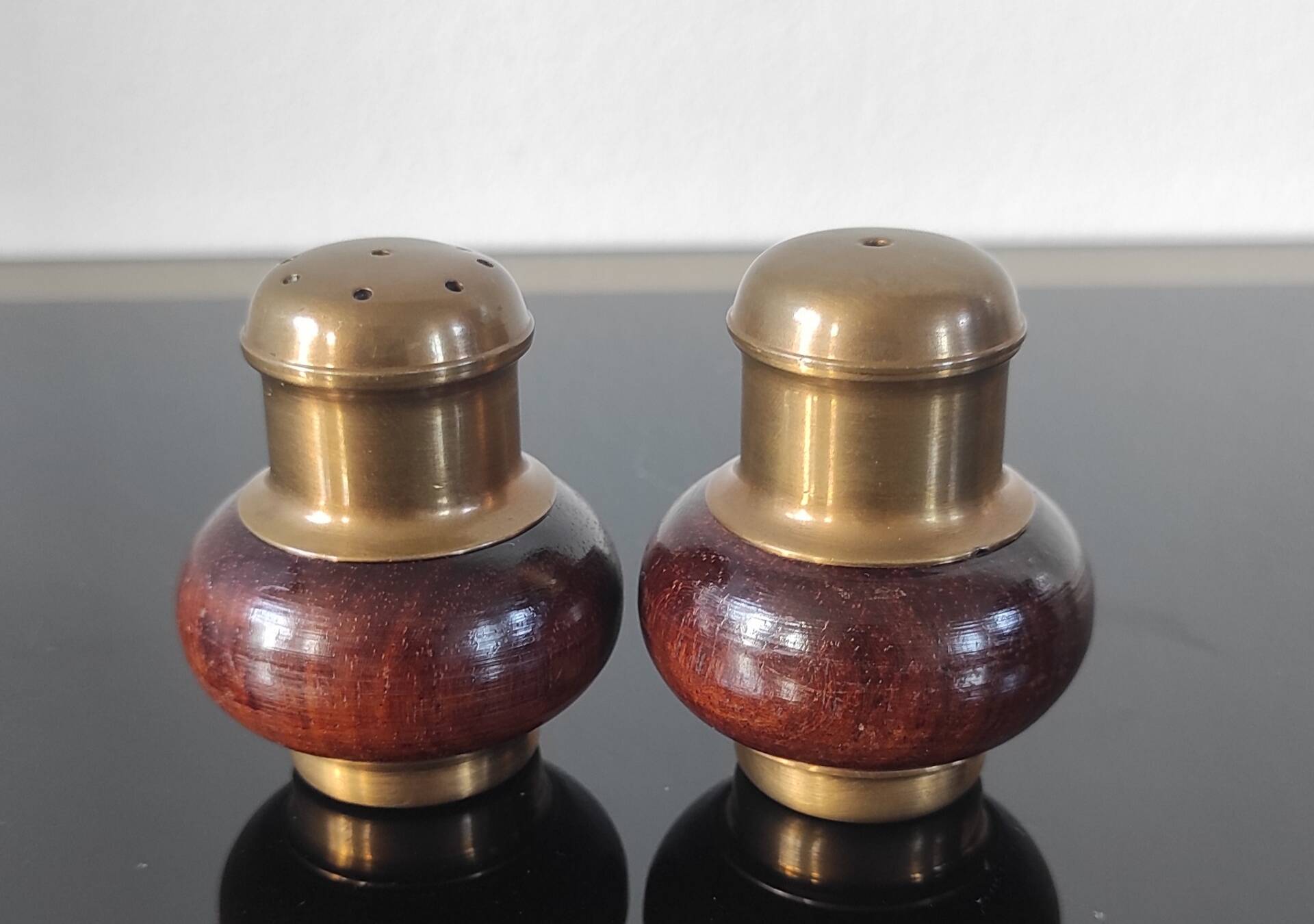 Vintage salt and pepper shaker duo in brass and turned wood.