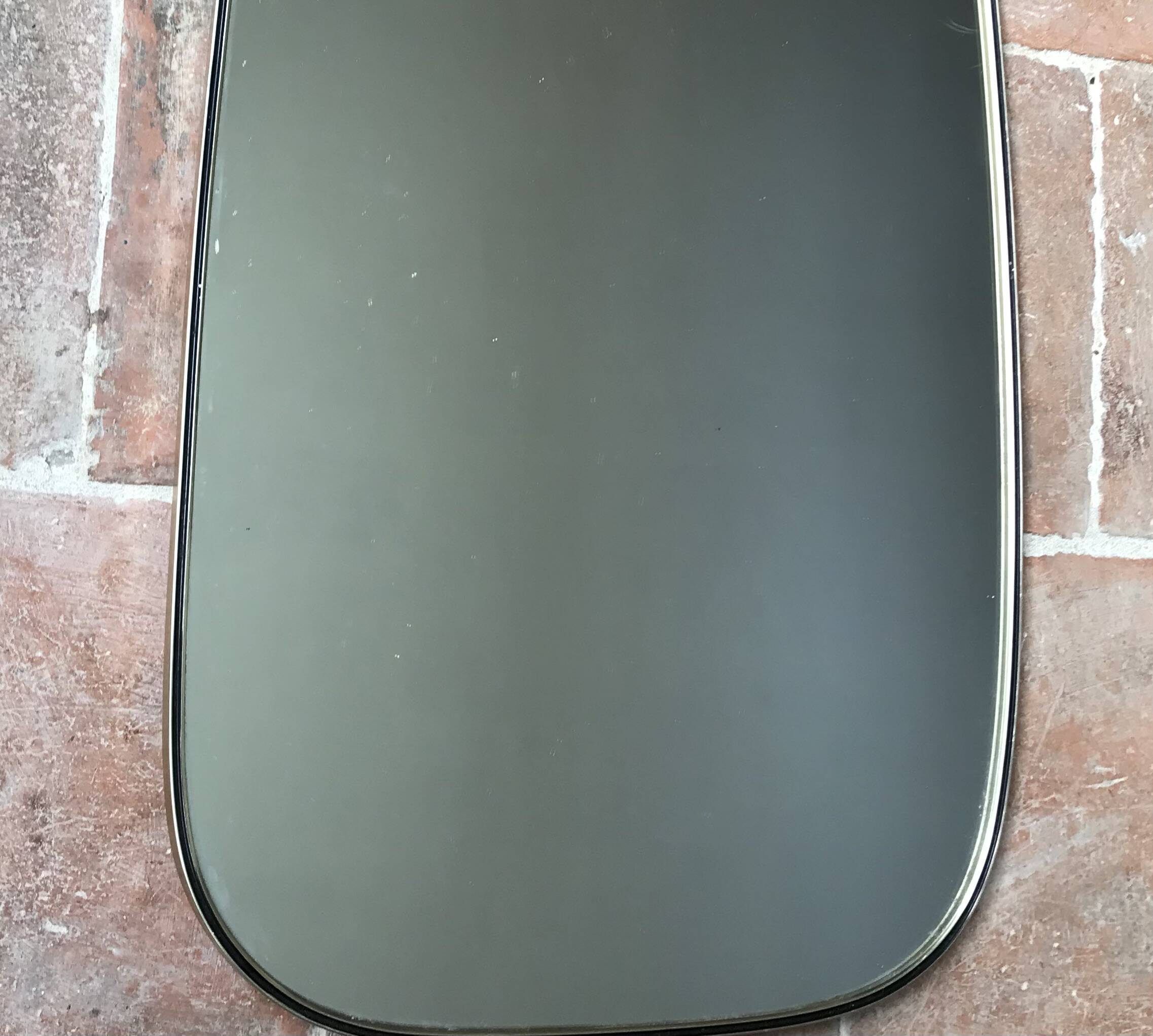 Vintage 1960 free-form mirror known as a retro mirror with a gold and black metal trim.