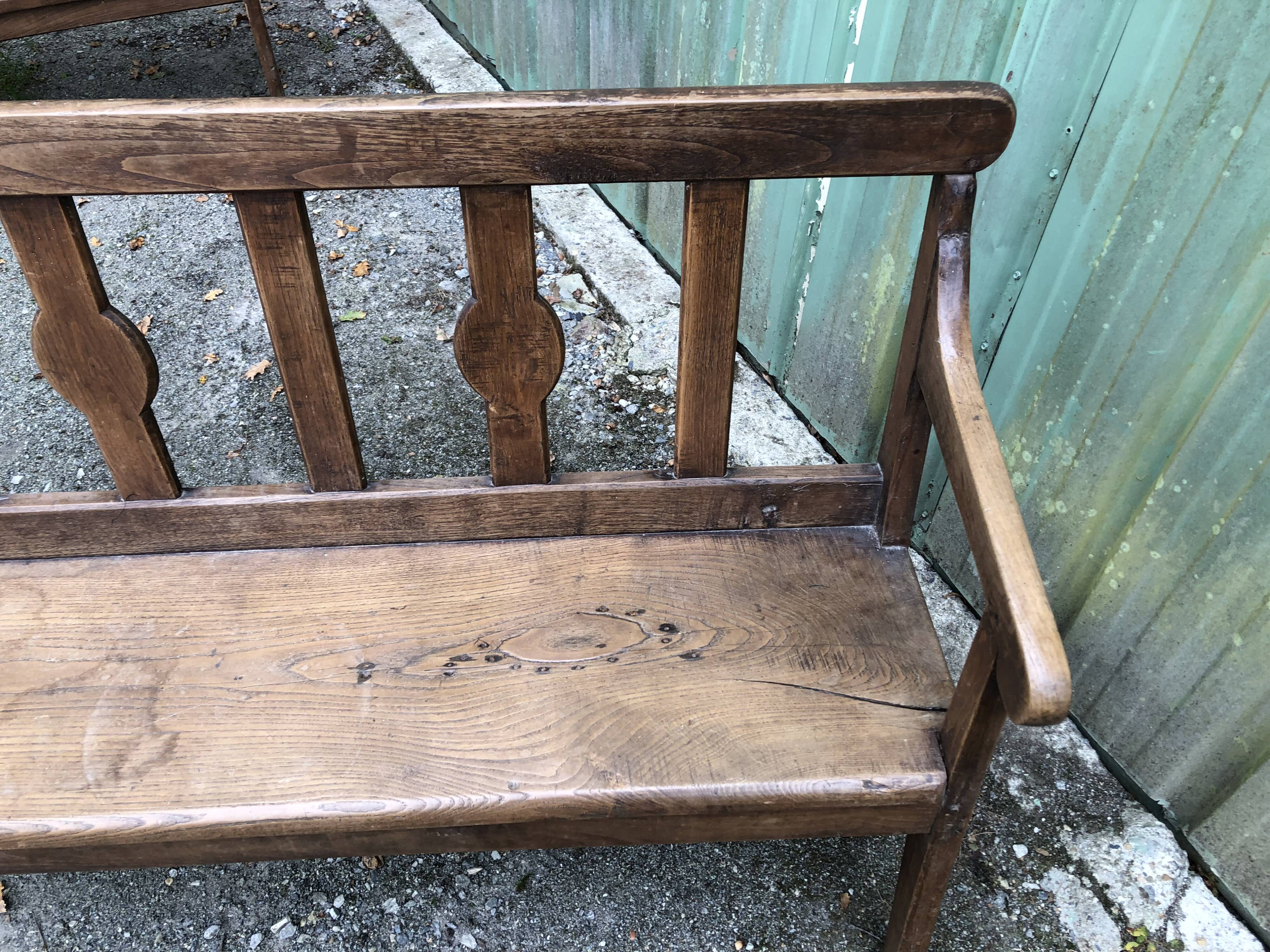 Duo of old solid oak benches with backs and armrests.