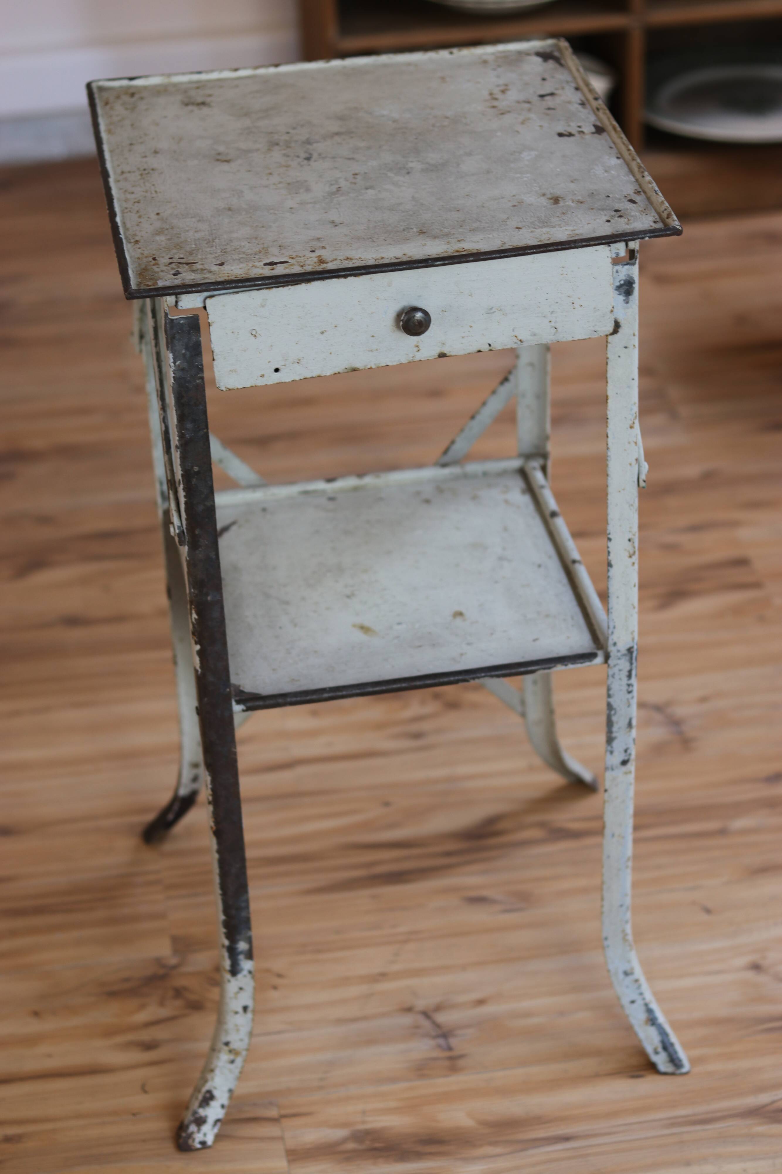 Painted metal side table, patinated white, with a drawer and two shelves