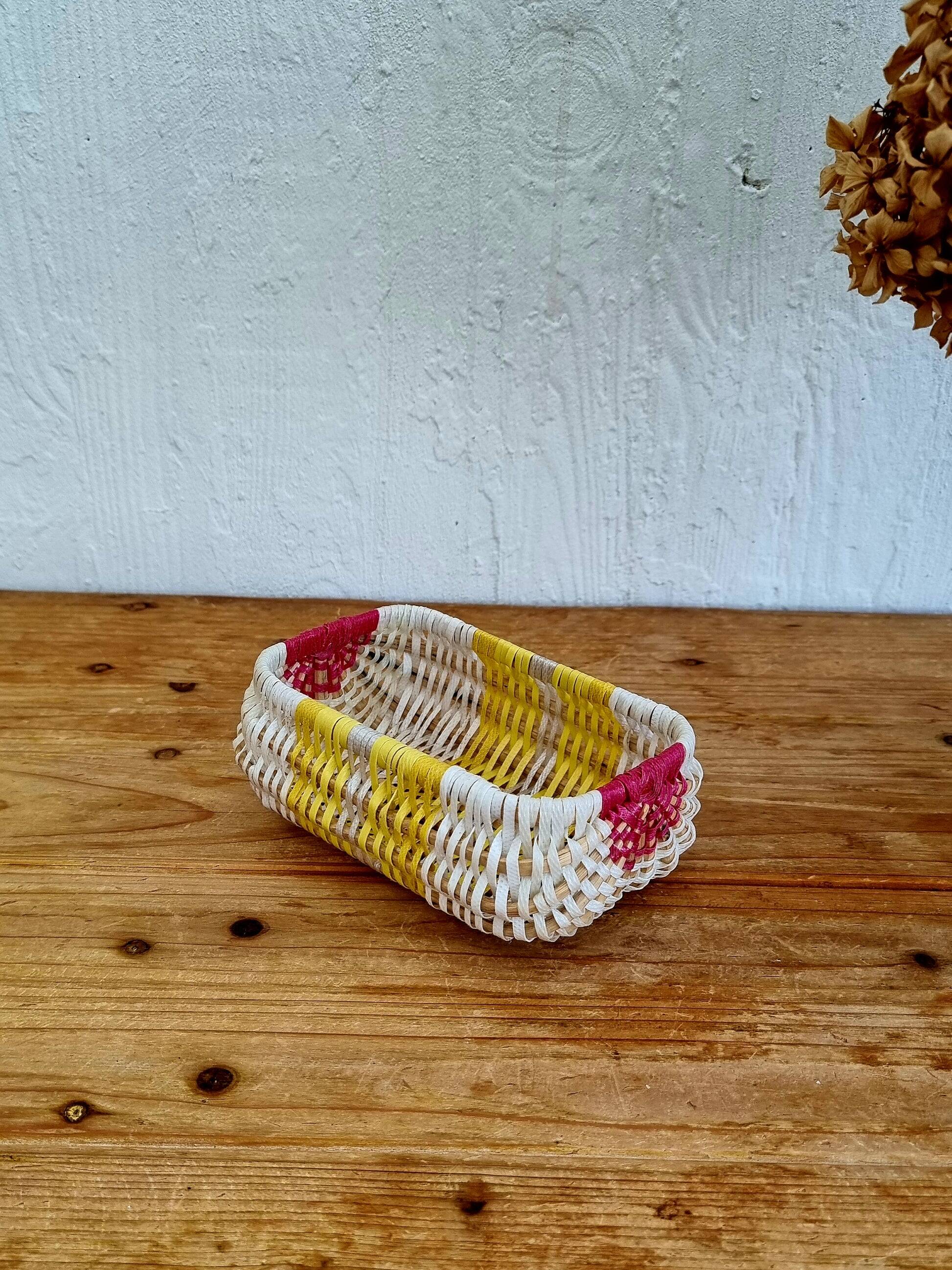 Vintage woven basket in yellow, white, and pink plastic.