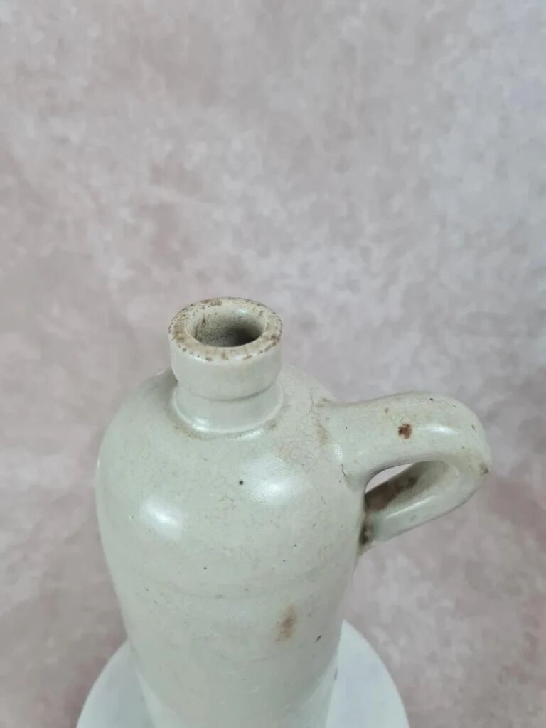 Antique beige glazed stoneware bottle from the 19th century, with a handle, vintage decor.