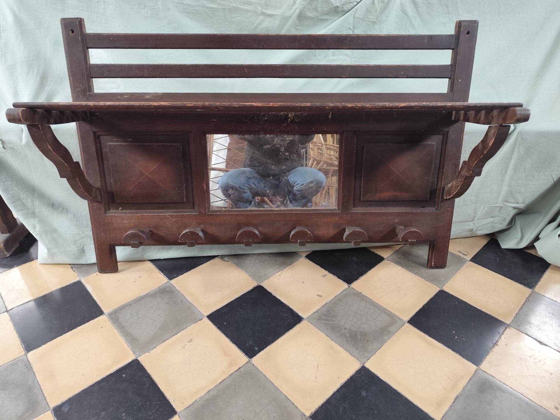 Wall-mounted coat rack with mirror and hat holder.