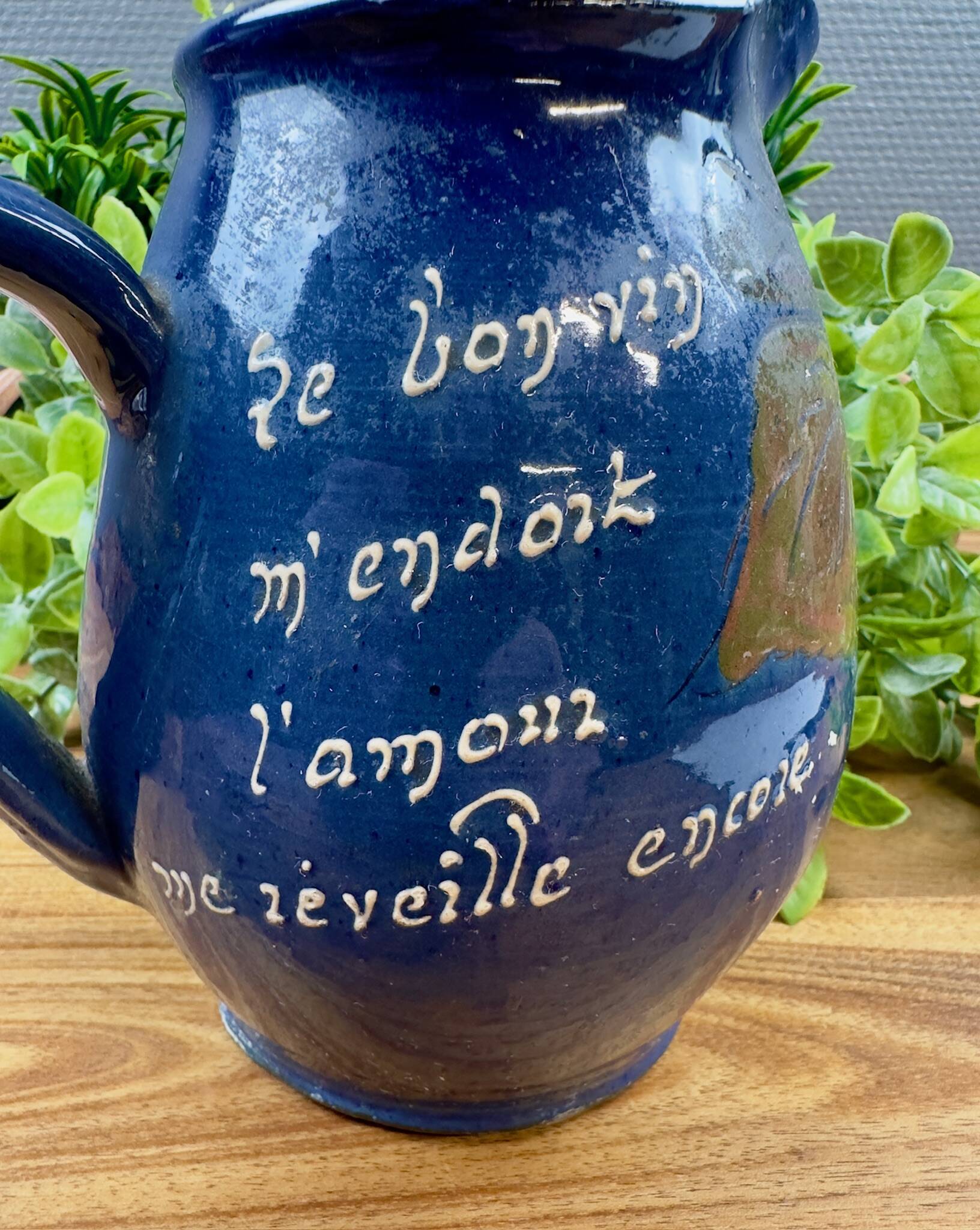 Blue ceramic pitcher with vintage artisan inscription decoration.