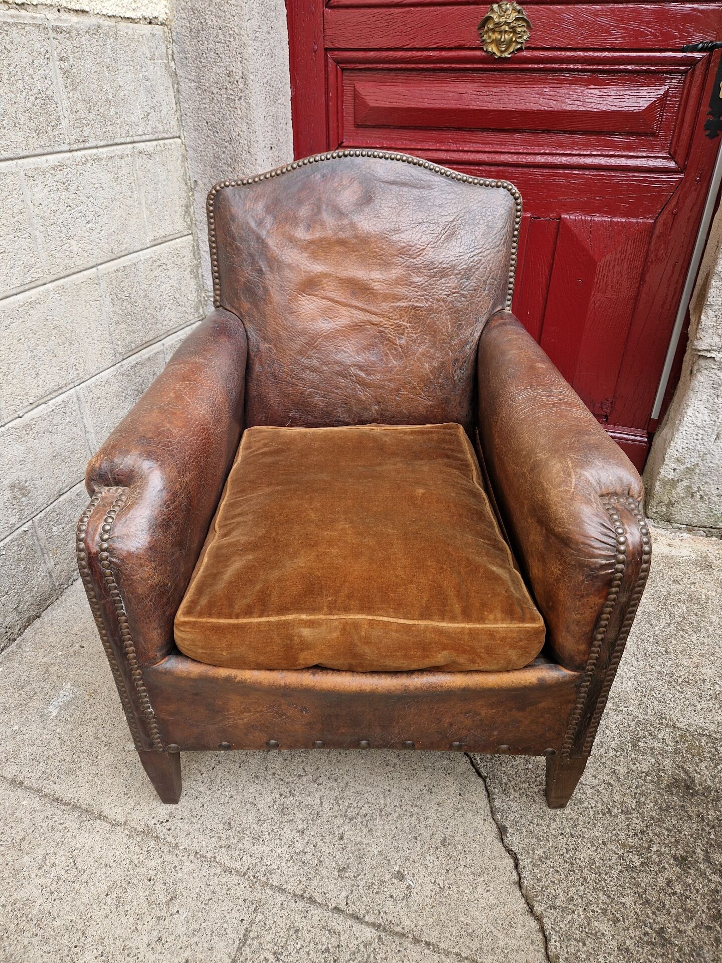 Antique club chair in patinated brown leather, early 20th century English style.
