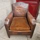 Antique club chair in patinated brown leather, early 20th century English style.