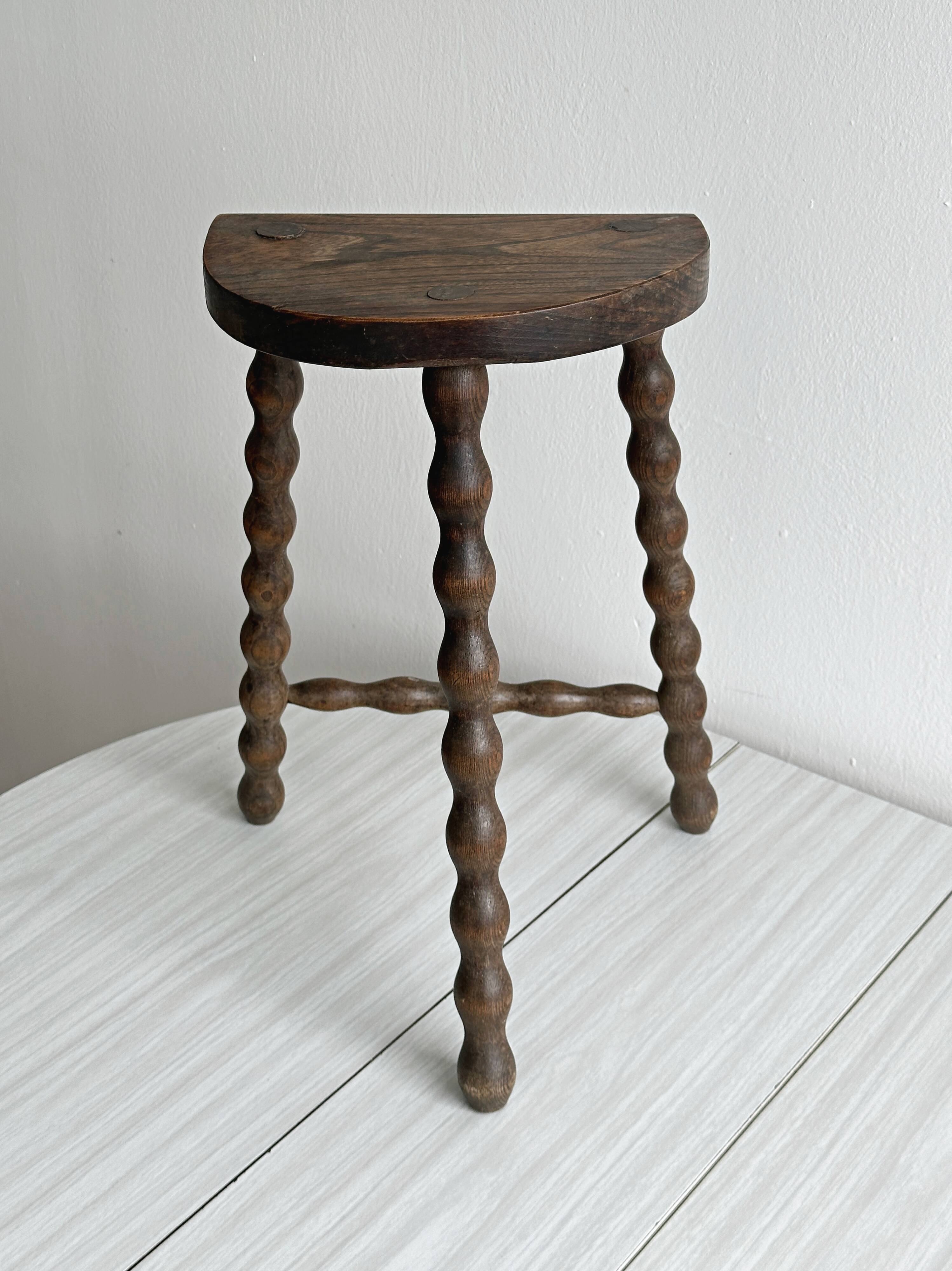 Three-legged demi-lune stool made of turned wood