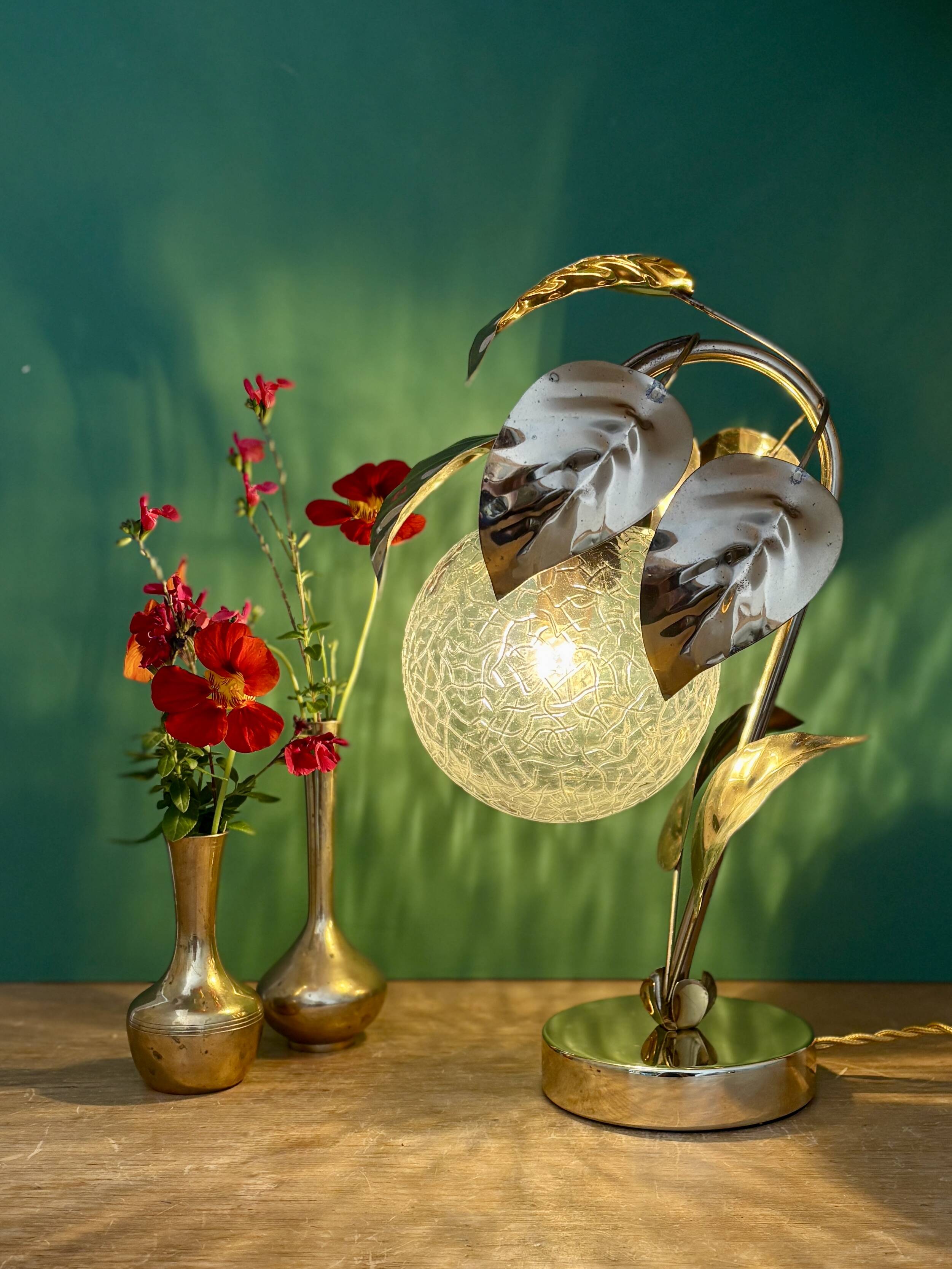 Vintage lamp with brass leaf design and transparent glass globe.