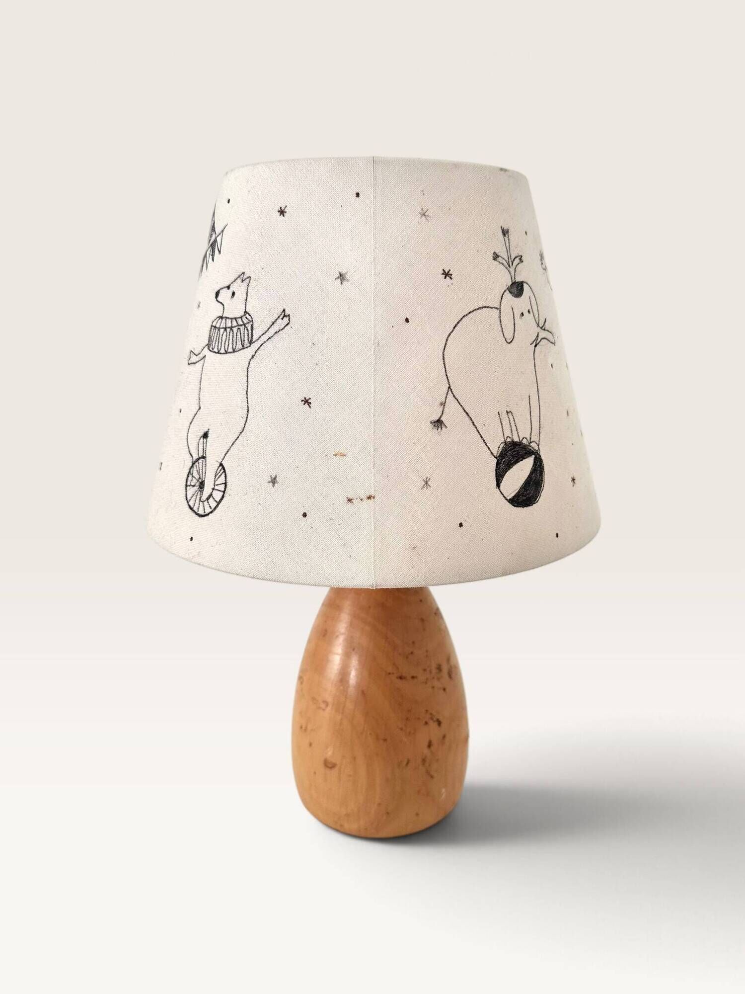 Wood-turned lamp with a hand-drawn lampshade, circus patterns.