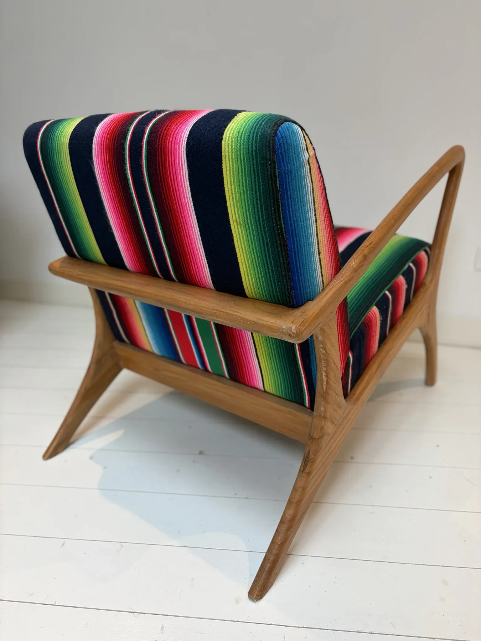 Scandinavian-style armchair in curved wood and colourful striped fabric.
