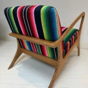 Scandinavian-style armchair in curved wood and colourful striped fabric.