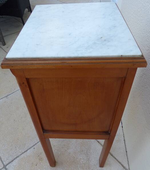Antique bedside table with its marble top and white earthenware interior