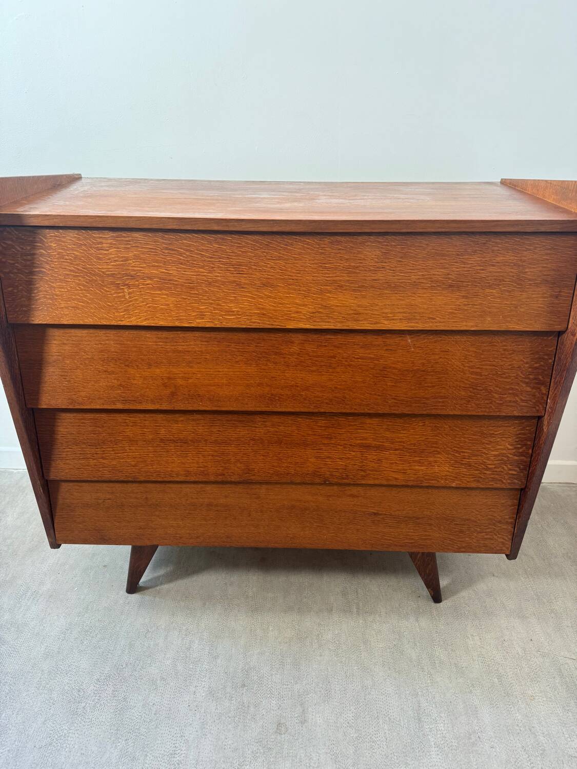Vintage wooden chest of drawers with tapered legs.