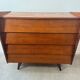 Vintage wooden chest of drawers with tapered legs.