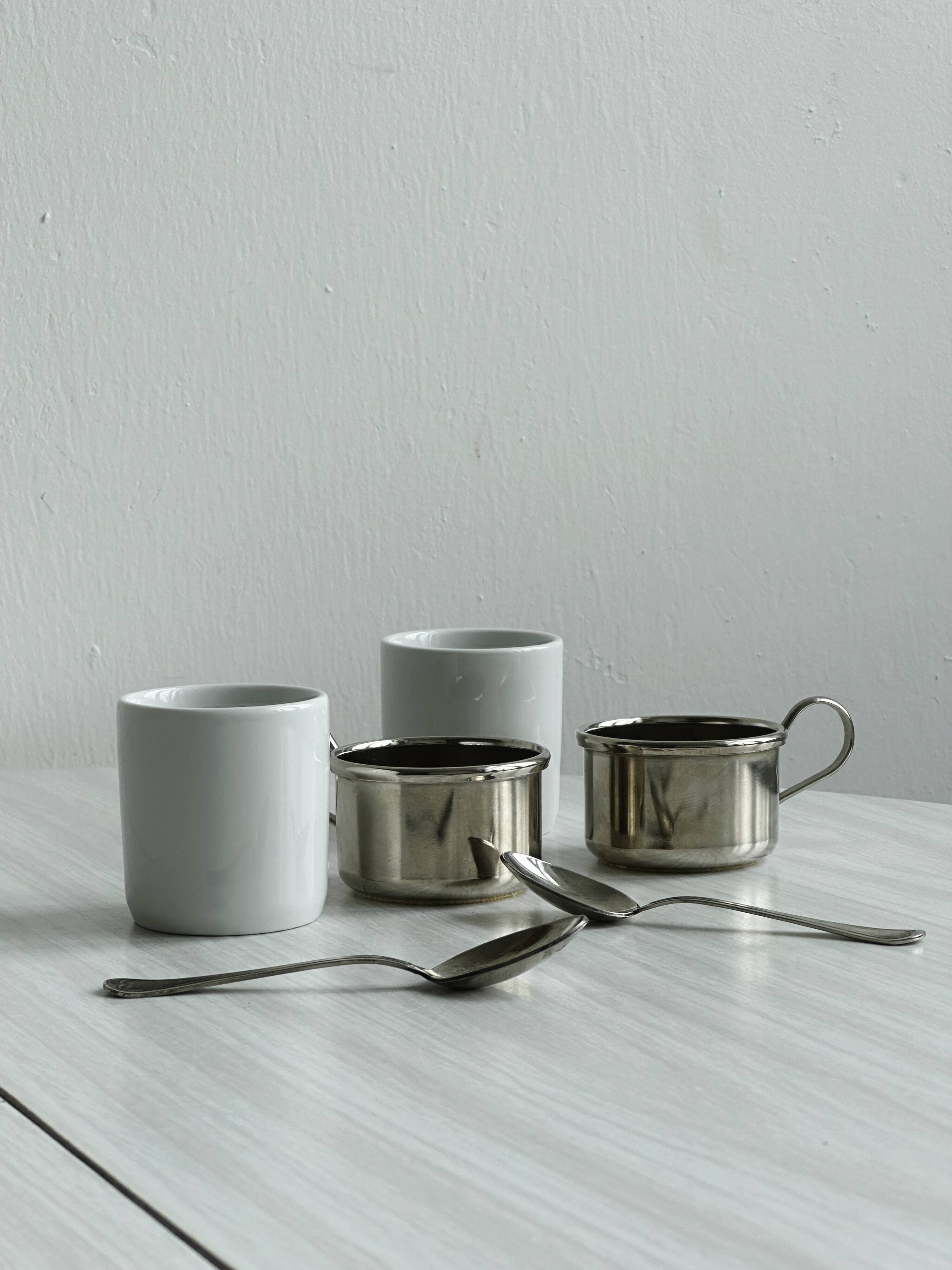 2 porcelain cups with metal supports and small spoons.