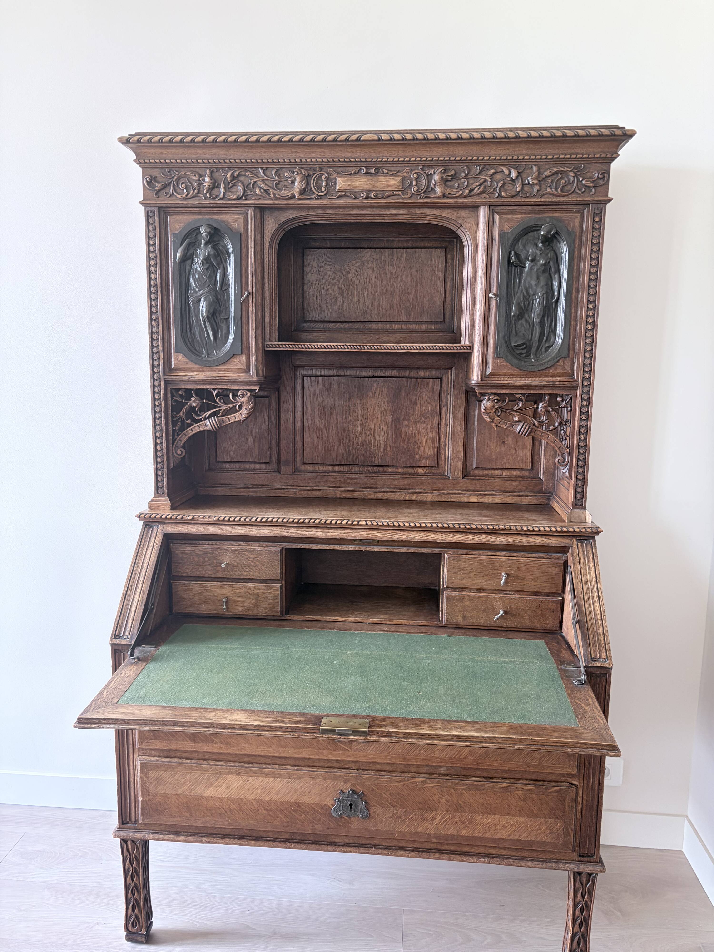 Large secretary with a drop-down front in carved oak, neo-Renaissance style.