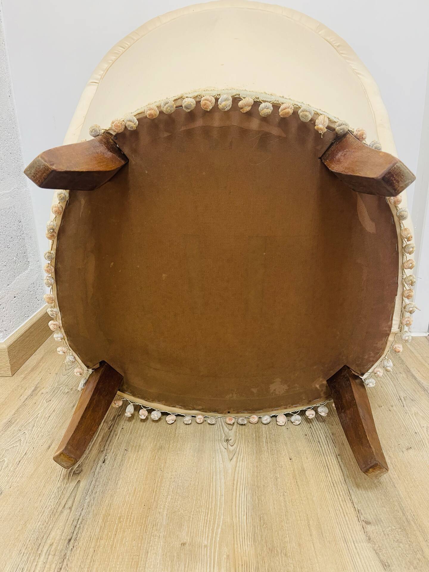 Pale pink upholstered armchair with wooden legs.