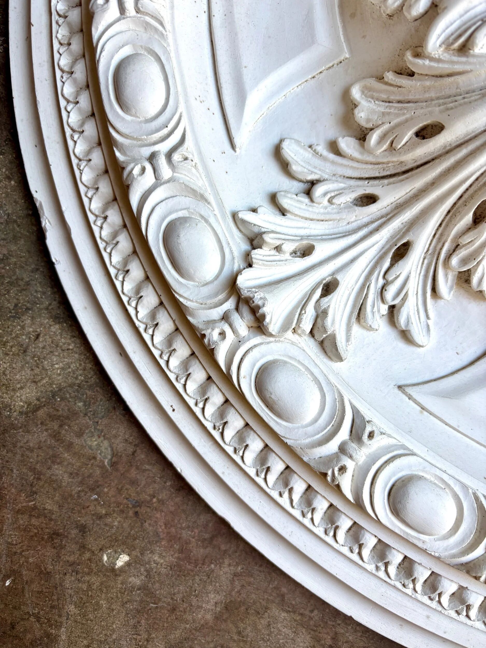 Rosette on white background, decorated with scrolls and beaded frieze ⌀ 61 cm